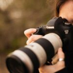 Close-up of female photographer using a DSLR camera outdoors.